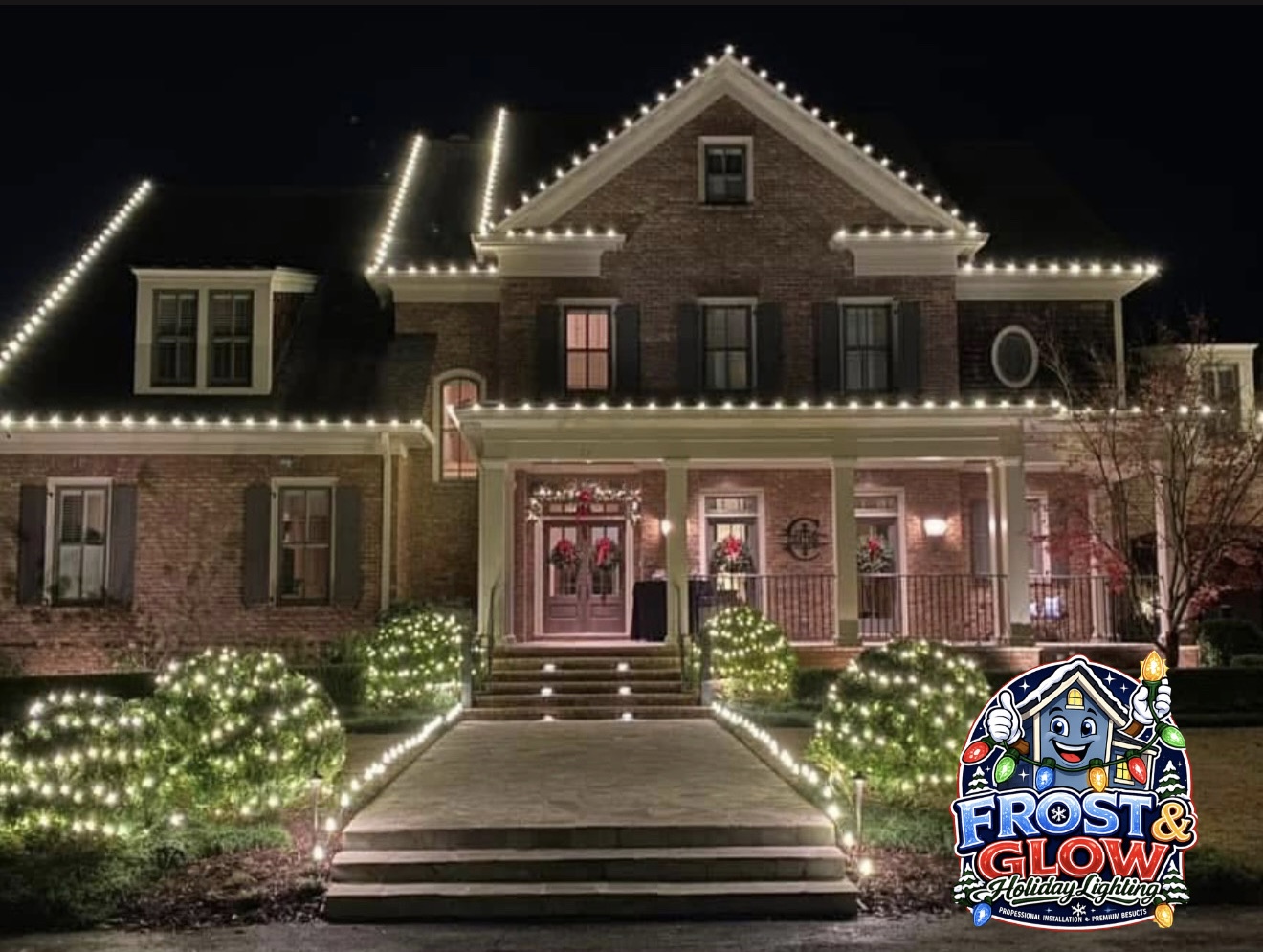 Clean bulb spacing across a multi-gable brick colonial with lit shrubs framing the walkway.
